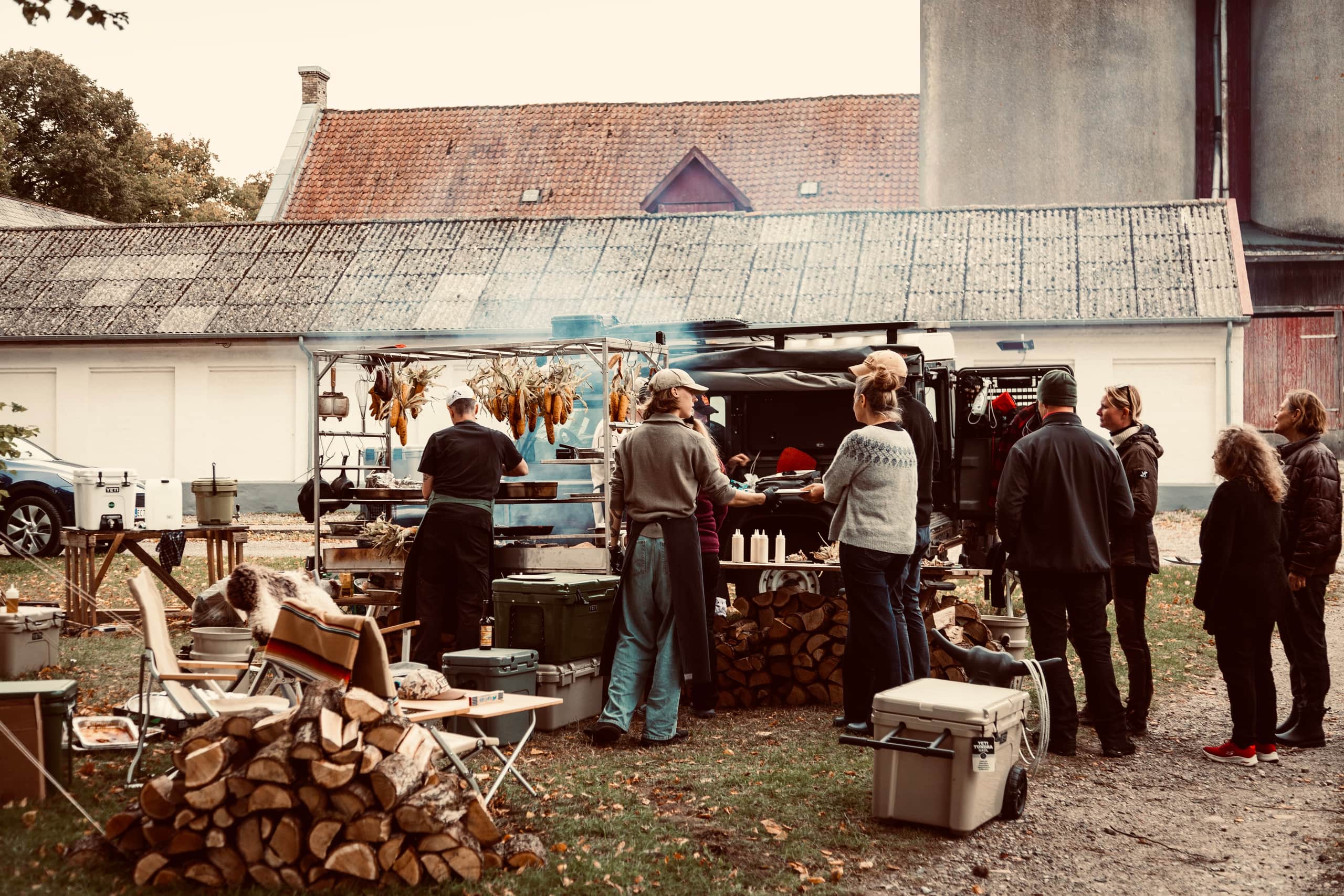 Gæster og kokke mødes ved et udendørs madlavningssted på Oremandsgaard Gods.